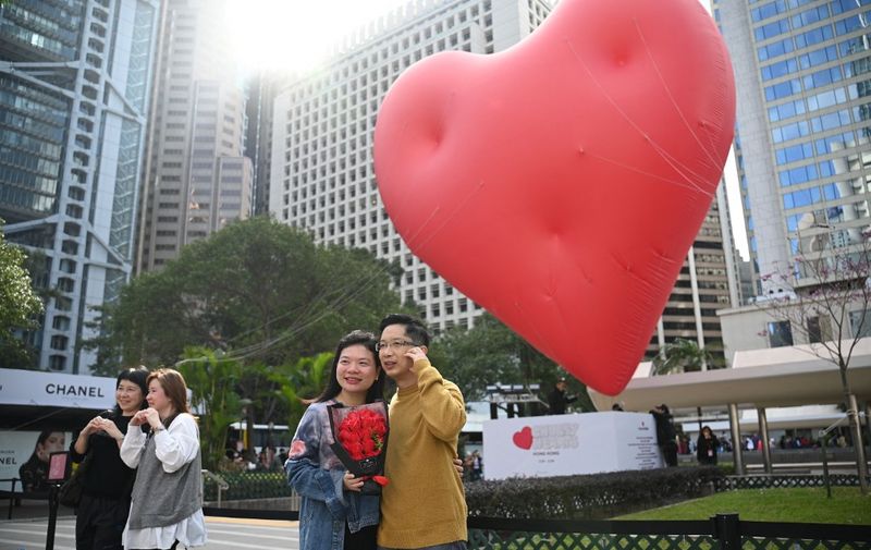 A couple pose for photos in front of a giant heart on Valentine's Day in Hong Kong on February 14, 2024. (Photo by Peter PARKS / AFP)