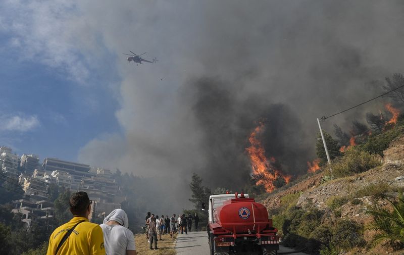 A wilfire burns near houses in the Panorama Voulas area, south of Athens on June 4, 2022. - A wildfire whipped by gale-force winds blazed through vegetation in a southern suburb of Athens, the fire brigade said, forcing residents to evacuate. (Photo by Louisa GOULIAMAKI / AFP)