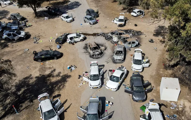 This aerial picture shows abandoned and torched vehicles at the site of the October 7 attack on the Supernova desert music Festival by Palestinian militants near Kibbutz Reim in the Negev desert in southern Israel on October 13, 2023. One month after Israel was wracked by Hamas attacks, life has been upended for both the Palestinians and Israel after it launched a war of reprisal in the Gaza Strip. The October 7 attacks by Hamas militants who stormed across from Gaza and struck kibbutzim and southern Israeli areas killed 1,400 people, mostly civilians, and deeply scarred the nation. The health ministry in Hamas-run Gaza says nearly 9,500 have been killed, two-thirds of them women and children, and mostly civilians. (Photo by Jack GUEZ / AFP)