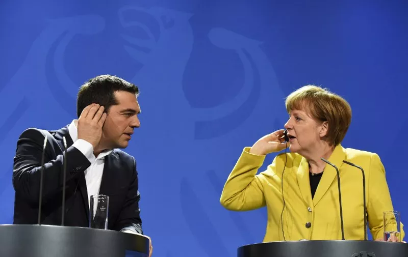 German Chancellor Angela Merkel (R) and Greek Prime Minister Alexis Tsipras hold their earpieces as they address a press conference following talks at the chancellery in Berlin, on March 23, 2015. AFP PHOTO / TOBIAS SCHWARZ