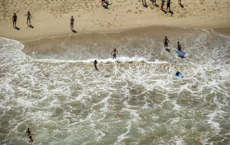 Surfers and beach goers play in the waters close to seals and sharks at Newcomb beach in Wellfleet, Massachusetts in Cape Cod on July 13, 2019. - On July 13 and 14 five great whites were spotted off Cape Cod, forcing three beaches to be briefly evacuated, the Atlantic White Shark Conservation Society reported. (Photo by JOSEPH PREZIOSO / AFP) / TO GO WITH AFP STORY "Wary swimmers share waves with deadly sharks off Cape Cod"