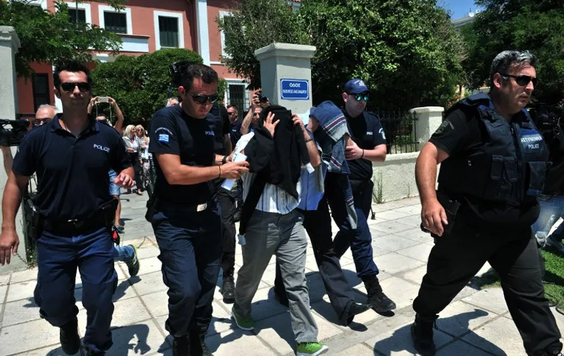 Turkish officers escorted by Greek police officers leave the courthouse of Alexandroupoli after appearing before a Greek prosecutor, on July 17, 2016.  
Eight Turkish military personnel who fled to Greece by helicopter after July 15 failed coup took no part in the putsch, their lawyer said, although a Greek government spokeswoman contradicted their account. The eight, who have claimed asylum in Greece, arrived by military helicopter on July 16, 2016 after sending a distress signal to authorities at the airport in northern Alexandroupoli. / AFP PHOTO / SAKIS MITROLIDIS