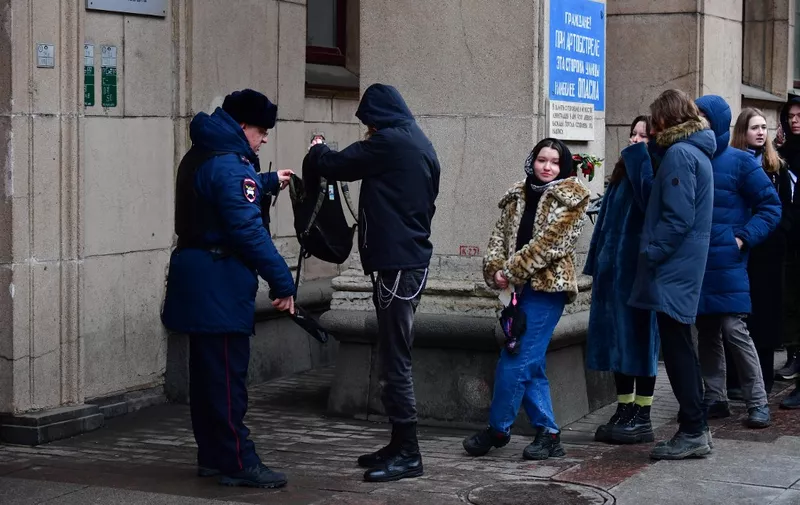 A police officer checks a man as he and other people queue outside a polling station during Russia's presidential election in Saint Petersburg on March 17, 2024. Russian opposition has called on people to head to the polls on March 17, 2024, at noon, in large numbers to overwhelm polling stations, in a protest which they hope will be a legal show of strength against President Vladimir Putin. (Photo by Olga MALTSEVA / AFP)