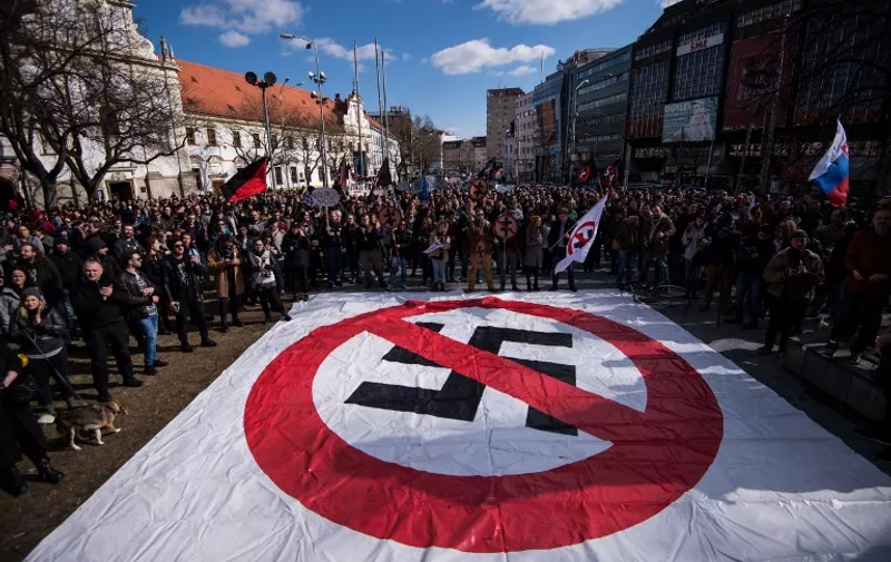 People hold a banner with a giant crossed out swastika as they attend an anti-fascist rally in Bratislava, Slovakia, on March 11, 2017.
Some 1500 people took part in the rally to protest against raising far-right powers in Slovak society. / AFP PHOTO / Vladimir Simicek