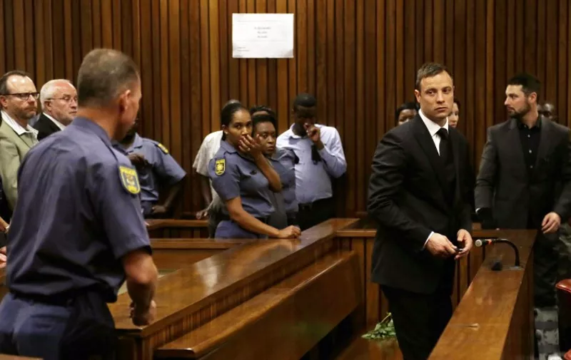 Paralympian Oscar Pistorius turns to leave the dock follwoing his sentencing at the high court in Pretoria, on October 21, 2014. South Africa's star athlete Pistorius was sentenced to five years imprisonment for the culpable homicide killing of his girlfriend Reeva Steenkamp and was also sentenced to three years, suspended for five years, for firing a pistol under a table at Tasha's restaurant in Johannesburg in January 2013. Background (R) is his brother Carl. AFP PHOTO/POOL / THEMBA HADEBE