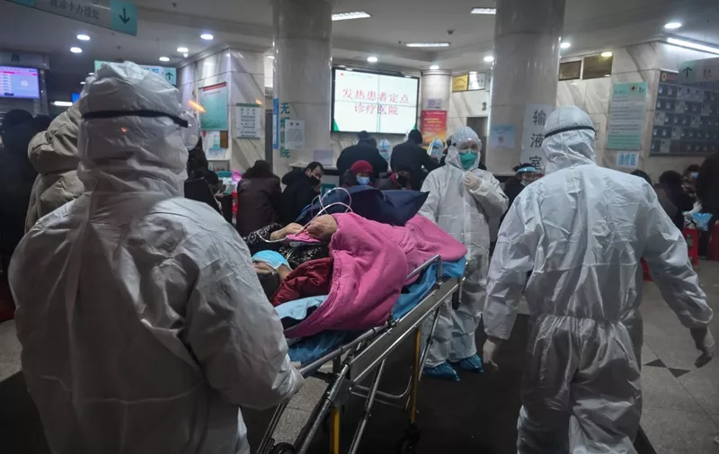In this photo taken on January 25, 2020, medical staff wearing protective clothing to protect against a previously unknown coronavirus arrive with a patient at the Wuhan Red Cross Hospital in Wuhan. - The number of confirmed deaths from a viral outbreak in China has risen to 54, with authorities in hard-hit Hubei province on January 26 reporting 13 more fatalities and 323 new cases. (Photo by Hector RETAMAL / AFP)