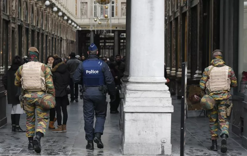 Belgian soldiers and police officers patrol at the entrance of the Galerie de la Reine near the Grand Place in Brussels on November 22, 2015. The Belgian capital was locked down for a second day on November 22 with police and troops on the streets as the authorities hunted for several suspects linked to the Paris attacks. Belgian officials were due to meet later to decide whether to extend the security alert in Brussels, imposed over fears jihadists were plotting similar strikes to the attacks in Paris which left 130 people dead on November 13. AFP PHOTO / JOHN THYS / AFP / JOHN THYS
