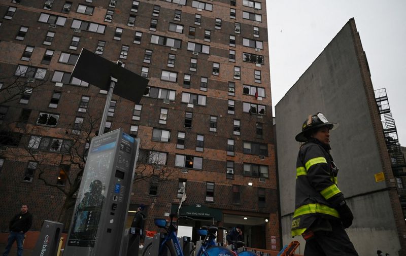 Firefighters work outside an apartment building after a fire in the Bronx, on January 9, 2022, in New York. - At least 19 people have died and dozens are injured after a fire tore through a high-rise apartment building in the New York borough of the Bronx, Mayor Eric Adams said Sunday. (Photo by Ed JONES / AFP)
