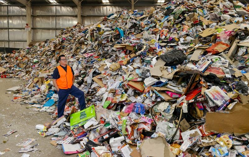 This photo taken on April 17, 2019 shows Northern Adelaide Waste Management Authority supervisor Thao Nguyen posing amongst items set for recycling at their site in Edinburgh, near Adelaide. - From grubby packaging engulfing small Southeast Asian communities to waste piling up in plants from the US to Australia, China's ban on accepting the world's used plastic has plunged global recycling into turmoil. (Photo by Brenton EDWARDS / AFP) / TO GO WITH Environment-waste-Malaysia-China-Australia, FOCUS by Sam Reeves and Poornima Weerasekara