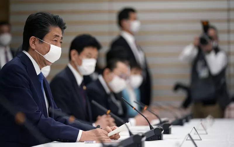 Japan's Prime Minister Shinzo Abe (L) speaks during a meeting at the headquarters for measures against the novel coronavirus disease, at the prime minister's official residence in Tokyo on April 6, 2020. - Abe said on April 6 the government plans to declare a state of emergency and proposed a stimulus package worth 1 trillion USD as new coronavirus infections spike in Tokyo and elsewhere. (Photo by Franck ROBICHON / POOL / AFP)