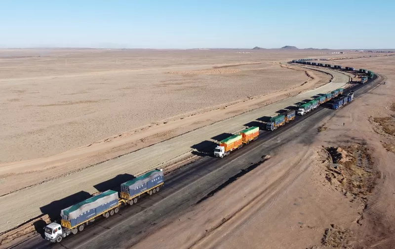 This aerial picture taken on October 16, 2021 shows trucks loaded with coal waiting near Gants Mod port at the Chinese border with Gashuun Sukhait, in Umnugovi province, in Mongolia. - Snaking across the barren Mongolian desert, a convoy crawls along the once-busy highway to the Chinese border -- its truckers desperate to finally deliver their cargo after months of brutal Covid delays and no pay. (Photo by Uugansukh Byamba / AFP) / TO GO WITH AFP STORY  China-environment-coal-energy by Khaliun Bayartsogt