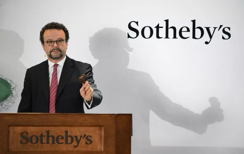 Head of Sotheby's international jewelery division, David Bennett holds the hammer during a "Magnificent Jewels and Noble Jewels" sales at the auction house on November 11, 2015 in Geneva. All eyes will turn to Sotheby's when its prized lot, dubbed "Blue Moon" with an estimated sale price between USD 35-55 million (about 32 597 560 to 51 224 737 euros) that will aim to shatter the record for a stone sold at an auction.  AFP PHOTO / FABRICE COFFRINI / AFP / FABRICE COFFRINI