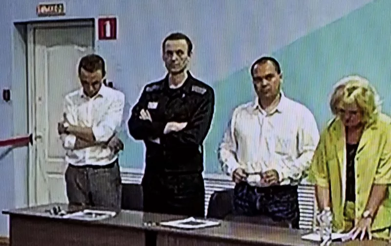 (FILES) A screen shows the already imprisoned Russian opposition figure Alexei Navalny (2L) as he listens to his verdict over a series of extremism charges at the IK-6 penal colony, a maximum-security prison some 250 kilometres (155 miles) east of Moscow, in the settlement of Melekhovo in the Vladimir region on August 4, 2023. Russian opposition leader Alexei Navalny died on February 16, 2024 at the Arctic prison colony where he was serving a 19-year-term, Russia's federal penitentiary service said in a statement. (Photo by Alexander NEMENOV / AFP)