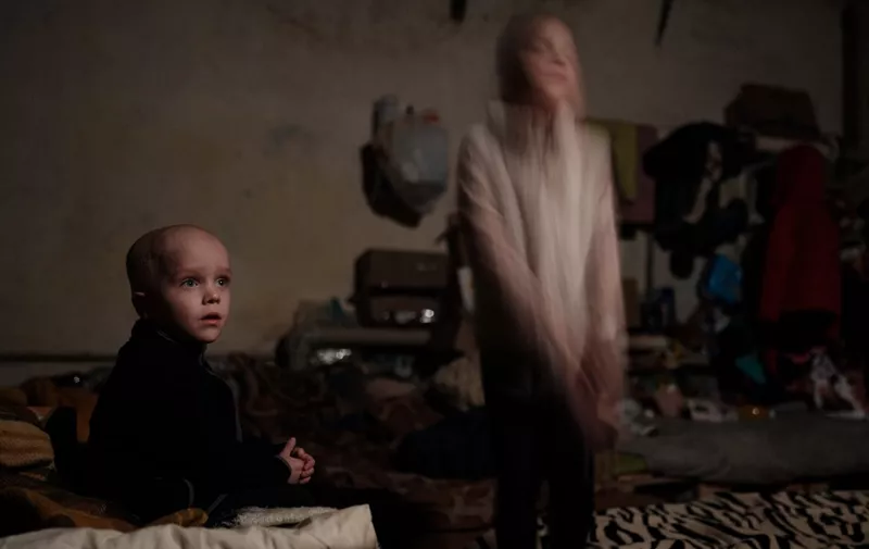 Sasha (L), 4, and his sister Ksenia, 8, children of a family that decided not to evacuate, pose in a bedroom in the basement shelter in Lysychansk, eastern Ukraine, on May 15, 2022, amid the Russian invasion of Ukraine. (Photo by Yasuyoshi CHIBA / AFP)