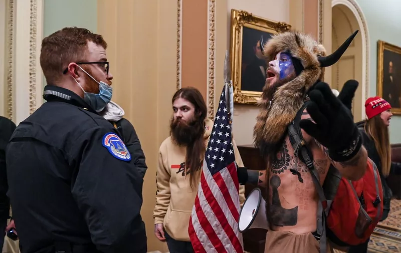 US Capitol police officers try to stop supporters of US President Donald Trump, including Jake Angeli (R), a QAnon supporter known for his painted face and horned hat, to enter the Capitol on January 6, 2021, in Washington, DC. - Demonstrators breeched security and entered the Capitol as Congress debated the a 2020 presidential election Electoral Vote Certification. (Photo by Saul LOEB / AFP)