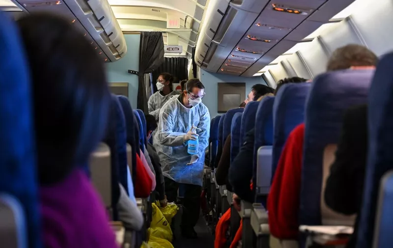 A crew member of an evacuation flight of French citizens from Wuhan gives passengers disinfectant during the flight to France on February 1, 2020, as they are repatriated from the coronavirus hot zone. - The nearly 200 passengers repatriated are expected to arrive in France on January 31, 2020 and will be be placed in quarantine for 14 days in a holiday center in Carry-le-Rouet, near Marseille, southern France. Some 7,700 cases have been confirmed in China, its country of origin, with at least 170 fatalities. The virus has spread from the city of Wuhan across China to more than 15 countries, with about 60 cases in Asia, Europe, North America and, most recently, the Middle East. (Photo by Hector RETAMAL / AFP)