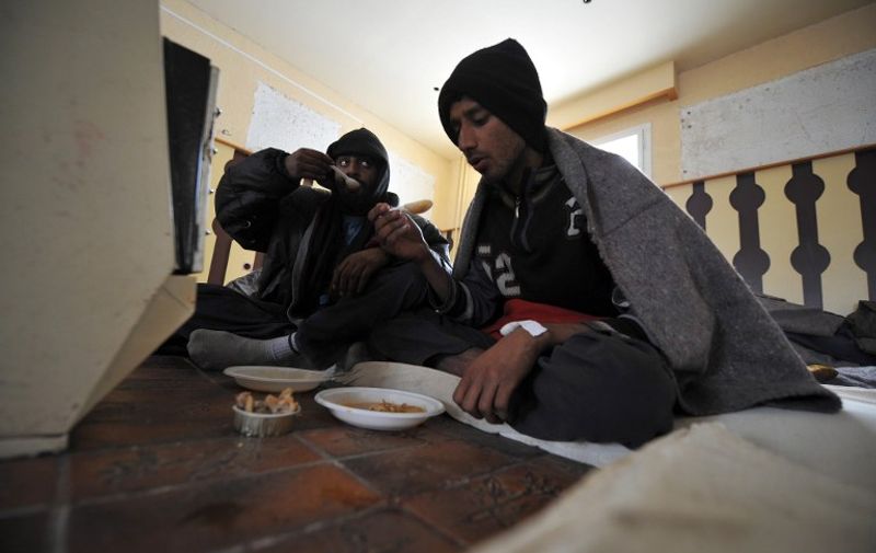 TO GO WITH AFP STORY BY JOVAN MATIC
Two migrants have  lunch near a gas heater at a temporary shelter in the northern Serbian town of Palic, 200 kilometers north of capital Belgrade, on February 9, 2012. Many of the immigrants were hoping that their next attempt to get to EU "promised land" by crossing the Hungarian border will be successful, but they ended up chattering in an abandoned restaurant in northern Serbia where they found refuge from Siberian cold that hit the region.  AFP PHOTO / ANDREJ ISAKOVIC