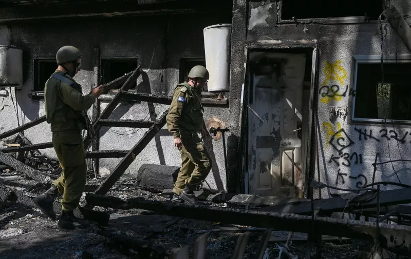 A picture taken during a media tour organised by the Israeli military shows soldiers near a damaged house at the Nir Oz kibbutz, one of the Israeli communities near the Gaza Strip attacked on October 7 by the Palestinian militant group Hamas, on October 30, 2023. Thousands of civilians, both Palestinians and Israelis, have died since October 7, 2023, after Palestinian Hamas militants based in the Gaza Strip entered southern Israel in an unprecedented attack triggering a war declared by Israel on Hamas with retaliatory bombings on Gaza. (Photo by YURI CORTEZ / AFP)