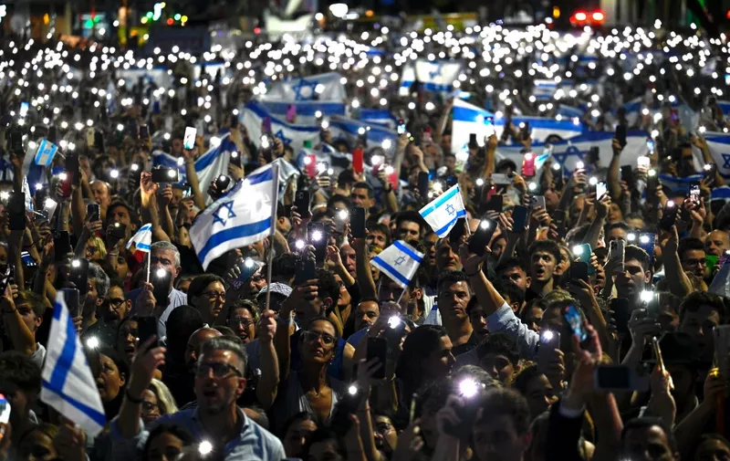 People hold Israeli national flags and display their lit mobile phones during a rally in support of the people of Israel, in Buenos Aires on October 9, 2023, following the October 7 shock deadly attack on Israel by Palestinian militant group Hamas. (Photo by Luis ROBAYO / AFP)