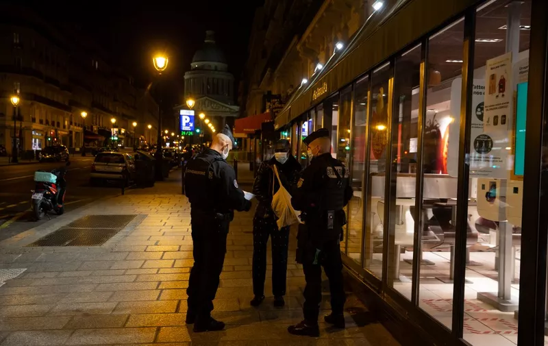 Police officers check the derogation of a pedestrian, on October 17, 2020 in Paris, at the start of a nighttime curfew implemented to fight the spread of the Covid-19 pandemic caused by the novel coronavirus. - About 20 million people in the Paris region and eight other French cities were facing a 9 pm-6 am curfew from October 17, after cases surged in what has once again become one of Europe's major hotpots. (Photo by Abdulmonam EASSA / AFP)
