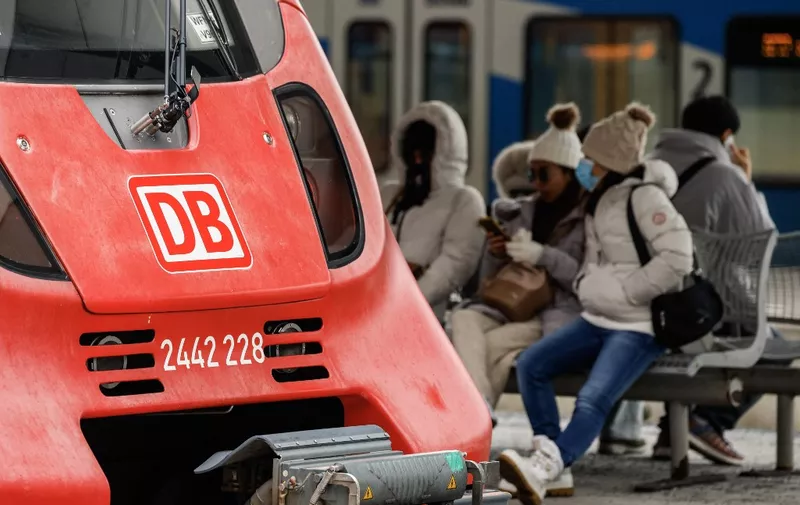 Passengers waiting for their trains sit next to a parked train in the main train station of Munich, southern Germany, during a wage strike by German train drivers on December 8, 2023. The GDL union said drivers of freight trains and of passenger trains had been called on to strike from December 7, 2023 evening to December 8, 2023 in the evening. It is their second walkout in weeks, in mid-November, train drivers staged a 20-hour strike that led to the cancellation of some 80 percent of long-distance trains nationwide. (Photo by Michaela Rehle / AFP)