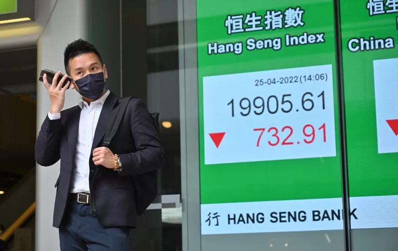A man uses his phone next to a sign showing the numbers for the Hang Seng Index before the close, as Hong Kong shares  fell  on April 25, 2022. (Photo by Peter PARKS / AFP)