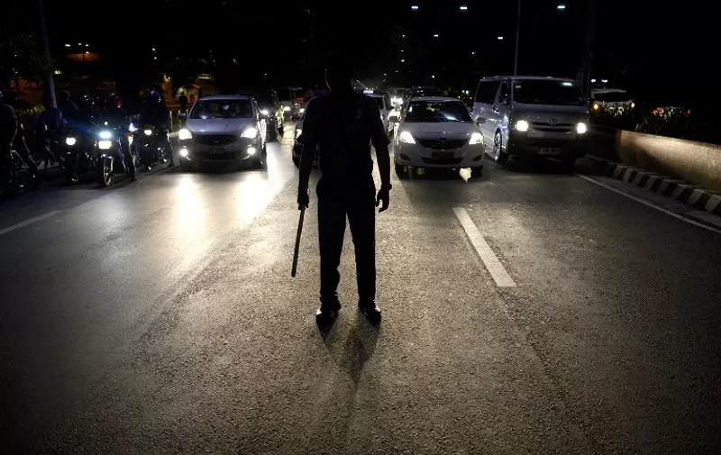 A police officer holds a truncheon as he manage the traffic in front of the US embassy as student hold a protest to show their demand to junk the Enhanced Defense Cooperation Agreement (EDCA) in Manila on January 20, 2016. The Philippines is set to offer the US military use of eight bases, a military spokesman said on January 13, after the country's supreme court upheld a security agreement with Washington forged in the face of rising tensions with China. AFP PHOTO / NOEL CELIS / AFP / MARK NAVALES
