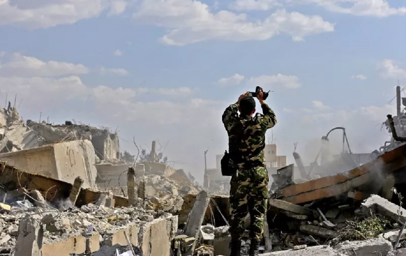 A Syrian soldier inspects the wreckage of a building described as part of the Scientific Studies and Research Centre (SSRC) compound in the Barzeh district, north of Damascus, during a press tour organised by the Syrian information ministry, on April 14, 2018.
The United States, Britain and France launched strikes against Syrian President Bashar al-Assad's regime early on April 14 in response to an alleged chemical weapons attack after mulling military action for nearly a week. Syrian state news agency SANA reported several missiles hit a research centre in Barzeh, north of Damascus, "destroying a building that included scientific labs and a training centre". / AFP PHOTO / LOUAI BESHARA
