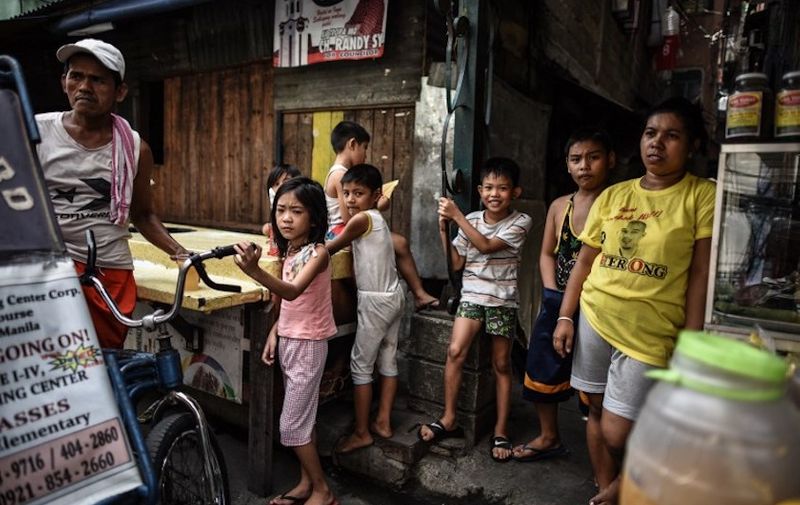 Filipino children stand near their houses ahead of the presidential and vice presidential elections in Tondo, Manila on May 7, 2016. - Mass murder advocate Rodrigo Duterte heads into Saturday's final rallies of an extraordinary Philippine presidential campaign as the shock favourite, but with rivals still having a chance to counter his profanity-laced populist tirades. (Photo by MOHD RASFAN / AFP)