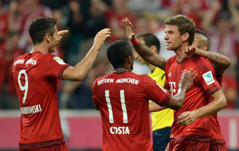 Bayern Munich's midfielder Thomas Mueller (R) celebrates scoring the 4-0 goal with his team-mates during the German first division Bundesliga football match FC Bayern Munich vs Hamburger SV at the Allianz Arena in Munich, southern Germany, on August 14, 2015. The match is the first of the 2015/2016 season. AFP PHOTO / DPA / SVEN HOPPE  +++ GERMANY OUT +++

RESTRICTIONS: DURING MATCH TIME: DFL RULES TO LIMIT THE ONLINE USAGE TO 15 PICTURES PER MATCH AND FORBID IMAGE SEQUENCES TO SIMULATE VIDEO. 
== RESTRICTED TO EDITORIAL USE ==
FOR FURTHER QUERIES PLEASE CONTACT DFL DIRECTLY AT + 49 69 650050.