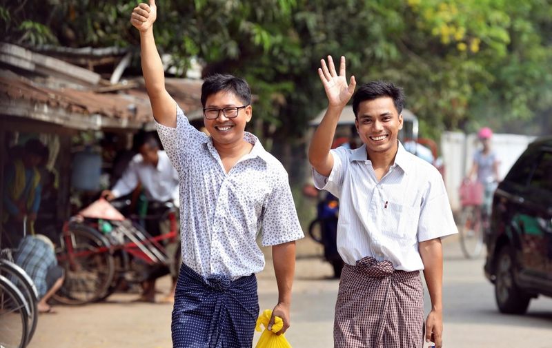 Reuters journalists Wa Lone (L) and Kyaw Soe Oo gesture as they walk to Insein prison gate after being freed in a presidential amnesty in Yangon on May 7, 2019. - Two Reuters journalists who had been jailed for their reporting on the Rohingya crisis in Myanmar walked out of prison on May 7, freed in a presidential amnesty after a global campaign for their release. (Photo by ANN WANG / POOL / AFP)