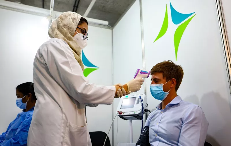 A health worker checks a man's temperature before receiving a dose of vaccine against the coronavirus at a vaccination centre set up at the Dubai International Financial Center in the Gulf emirate of Dubai, on February 3, 2021. - The United Arab Emirates, which includes Dubai and six other emirates, has suffered a spike in cases after the holiday period.
It was among the first to launch a vast vaccination campaign in December 2020 for its population of nearly 10 million and has administered at least three million doses to more than a quarter of its population, second only to Israel in the global race, according to the German data agency Statista. (Photo by Karim SAHIB / AFP)
