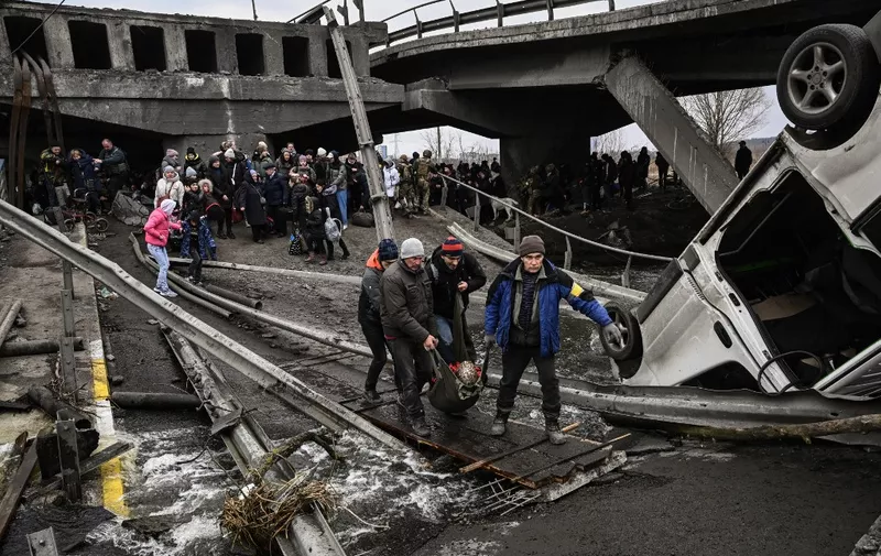 People cross a destroyed bridge as they evacuate the city of Irpin, northwest of Kyiv, during heavy shelling and bombing on March 5, 2022, 10 days after Russia launched a military in vasion on Ukraine. (Photo by Aris Messinis / AFP)