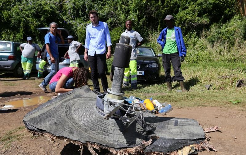Local ecological association members and volunteers stand behind debris found on August 11, 2015 in the eastern part of Sainte-Suzanne, on France's Reunion Island in the Indian Ocean, during search operations for the missing MH370 flight conducted by French army forces and local associations. The hunt for more wreckage from the missing MH370 resumed on Reunion island on August 9 after being suspended due to bad weather, local officials said.  A wing part was found on the island in late July and confirmed by the Malaysian prime minister to be part of the Boeing 777 which went missing on March 8, 2014 with 239 people onboard. AFP PHOTO / RICHARD BOUHET