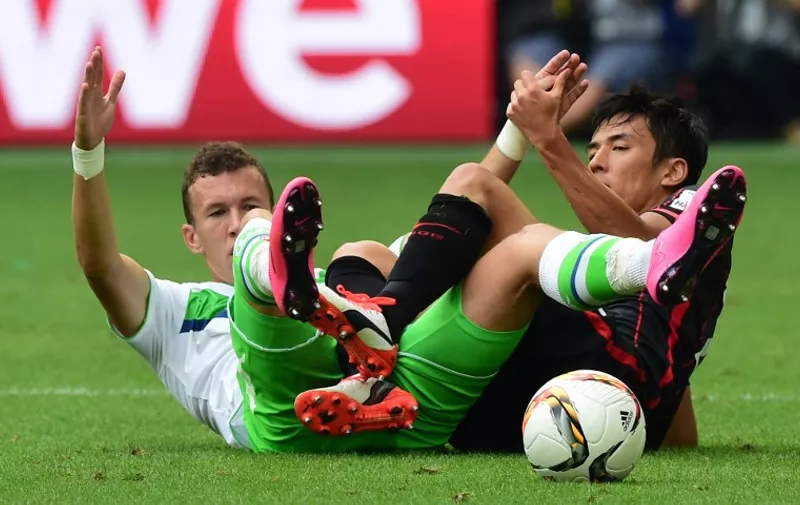 Wolfsburg's Croatian midfielder Ivan Perisic (L) and Frankfurt's Japanese midfielder Makoto Hasebe fall to the ground during the German first division Bundesliga football match VfL Wolfsburg vs Eintracht Frankfurt in Wolfsburg, northern Germany, on August 16, 2015.  AFP PHOTO / JOHN MACDOUGALL

RESTRICTIONS: DURING MATCH TIME: DFL RULES TO LIMIT THE ONLINE USAGE TO 15 PICTURES PER MATCH AND FORBID IMAGE SEQUENCES TO SIMULATE VIDEO. 
== RESTRICTED TO EDITORIAL USE ==
FOR FURTHER QUERIES PLEASE CONTACT DFL DIRECTLY AT + 49 69 650050.