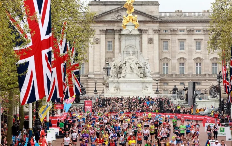 Runners pass Buckingham Palace as they make their way along The Mall towards the finish line during the 2015 London Marathon in central London on April 26, 2015. Eliud Kipchoge led a Kenyan clean sweep of the podium places as he won the men's London Marathon on Sunday in an unofficial time of two hours, four minutes and 41 seconds.   AFP PHOTO / SEAN DEMPSEY