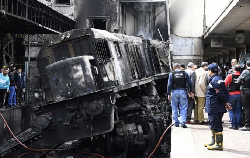 Fire fighters and onlookers gather at the scene of a fiery train crash at the Egyptian capital Cairo's main railway station on February 27, 2019. - The crash killed at least 20 people, Egyptian security and medical sources said.
The accident, which sparked a major blaze at the Ramses station, also injured 40 others, the sources said. (Photo by Khaled DESOUKI / AFP)