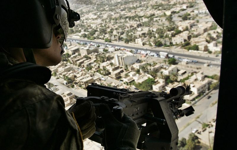 United States Army helicopter gunner Daniel Brown scans the Iraqi capital Baghdad, on route from the heavily-fortified Green Zone to Baghdad International Airport 02 October 2007. Britain's Gordon Brown arrived Tuesday in the southern city of Basra where he was to visit British troops on the second leg of his maiden trip to Iraq as prime minister. AFP PHOTO/POOL/LEFTERIS PITARAKIS (Photo by LEFTERIS PITARAKIS / POOL / AFP)
