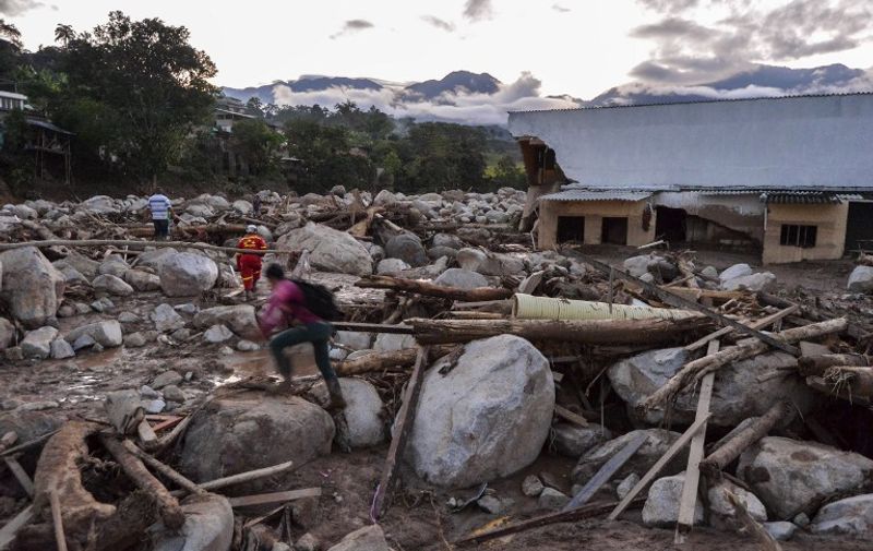 People walk through the rubble left by mudslides following heavy rains in Mocoa, Putumayo department, southern Colombia on April 1, 2017. 
A massive avalanche left more than 200 dead and hundreds of injured and disappeared on Saturday in southern Colombia, after heavy rains that have affected the Andean region, especially Peru and Ecuador. / AFP PHOTO / LUIS ROBAYO