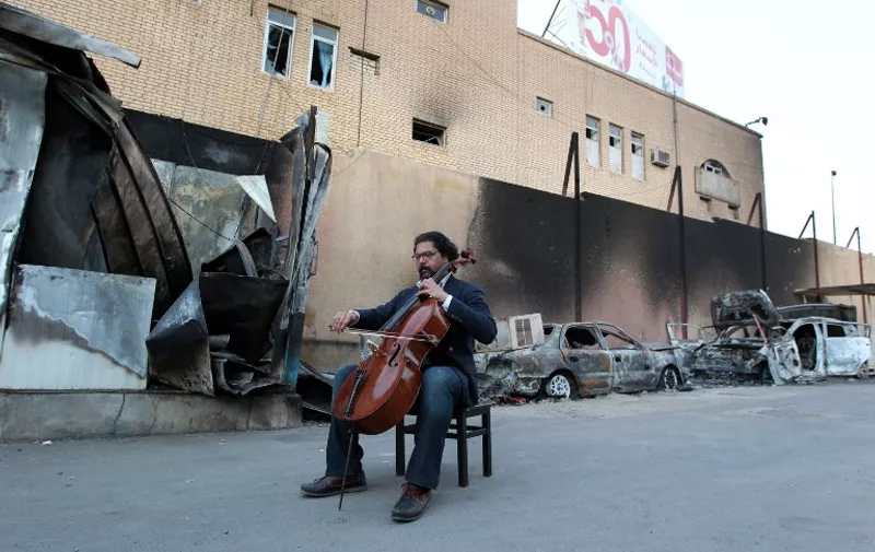 Karim Wasfi, former director for the Iraqi National Symphony Orchestra, plays on his cello next to debris in Baghdad's Sunni Adhamiya district on May 15, 2015, in a symbolic act of protest against violence. AFP PHOTO / SABAH ARAR