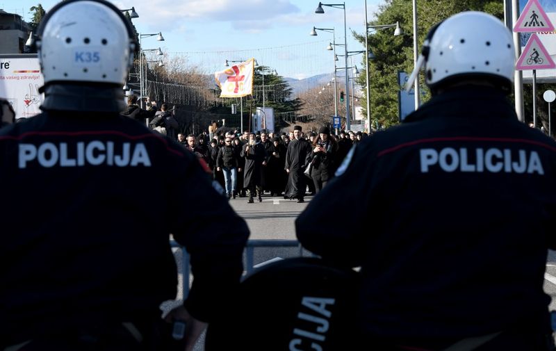 Serbian Orthodox Church clergy and believers stand in front of police on a bridge near the parliament, ahead of the vote on a controversial law on religious freedom in Podgorica on December 26, 2019. - More than a dozen Montenegrin opposition MPs were detained in parliament on December 27, 2019, after they violently protested a controversial law on religious freedom, which was passed after the group was taken away. The law has raised tensions in recent weeks between the government and a pro-Serb opposition which is close to the Serbian Orthodox Church (SPC), Montenegro's main religious body. Under the legislation, religious communities need to prove ownership of property from before 1918, when Montenegro lost its independence, in order to keep it. (Photo by Savo PRELEVIC / AFP)