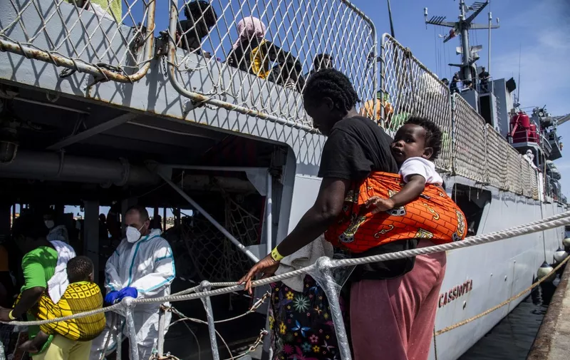 Migrants arrive in the harbour of Italian island of Lampedusa, before being transferred to Porto Empedocle in Sicily region, south Italy, by the Italian military ship Cassiopea, on September 15, 2023. The island's reception centre, built to house fewer than 400 people, was overwhelmed with men, women and children forced to sleep outside on makeshift plastic cots, many wrapped in metallic emergency blankets. Good weather has seen a surge in arrivals across Italy in recent days, with more than 5,000 people landing across the country on September 12, and almost 3000 the day after, according to updated interior ministry figures. (Photo by Alessandro SERRANO / AFP)