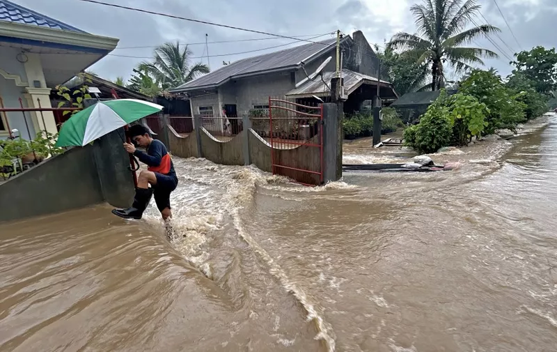 A man wades through floodwaters brought about by heavy rains at a residential neighbourhood in Propseridad town, Agusan del Sur province on southern Mindanao island on February 1, 2024. Floods and landslides triggered by torrential rain have killed six people in the Philippines, with one other person missing, rescuers said February 1. (Photo by Erwin MASCARINAS / AFP)