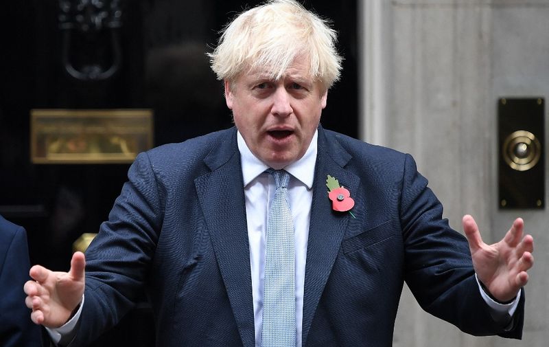 Britain's Prime Minister Boris Johnson gestures after purchasing a poppy from a fundraiser for the Royal British Legion in front of the Number 10 door in Downing Street in London on October 29, 2021. (Photo by Chris J RATCLIFFE / AFP)