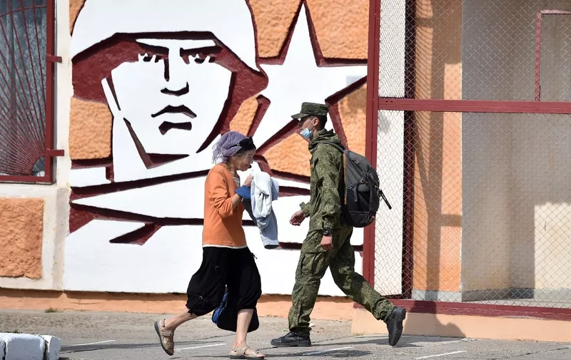 (FILES) A soldier and a woman walk past the headquarters of the Operative Group of the Russian Troops in the town of Tiraspol, the capital of Transnistria - Moldova's pro-Russian breakaway region on the eastern border with Ukraine, on September 11, 2021. Pro-Russian rebels in Moldova's breakaway region of Transnistria geared up for a rare meeting on February 28, 2024, amid fears the territory could open a new flashpoint in Moscow's conflict with neighbouring Ukraine. (Photo by Sergei GAPON / AFP)