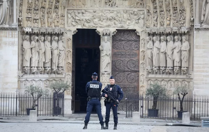 French police officers stand outside Notre-Dame-de Paris on April 16, 2019 in Paris in the aftermath of a fire that devastated the cathedral. - A raging fire that tore through Notre-Dame Cathedral in central Paris was extinguished, the city's fire service announced on April 16, around 15 hours after it first broke out. The blaze brought its towering spire and roof crashing to the ground, wiping out centuries of priceless heritage central to French culture and history. (Photo by LUDOVIC MARIN / POOL / AFP)