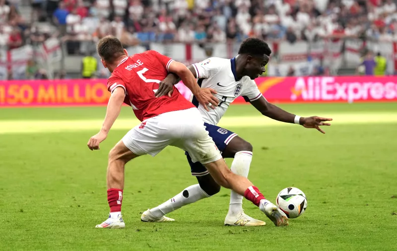 Denmark's Joakim Maehle, left, challenges England's Bukayo Saka, right, during a Group C match between Denmark and England at the Euro 2024 soccer tournament in Frankfurt, Germany, Thursday, June 20, 2024. (AP Photo/Sergei Grits)