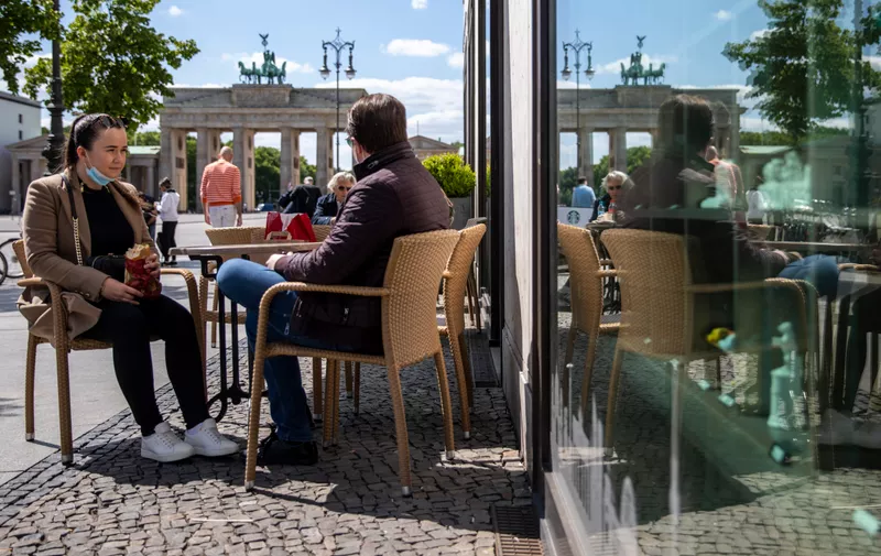BERLIN, GERMANY - MAY 15: People sit outside bakery near Brandenburg Gate on May 15, 2020 in Berlin, Germany. As authorities continue to ease lockdown restrictions nationwide businesses are reopening, tourism is becoming possible again and more children are returning to school. At the same time health experts are monitoring infection rates carefully for signs of any resurgence. (Photo by Maja Hitij/Getty Images)