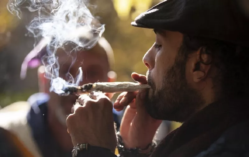 A man smokes a marijuana cigarette during a legalization party at Trinity Bellwoods Park in Toronto, Ontario, October 17, 2018. - Nearly a century of marijuana prohibition came to an end Wednesday as Canada became the first major Western nation to legalize and regulate its sale and recreational use. Scores of customers braved the cold for hours outside Tweed, a pot boutique in St John's, Newfoundland that opened briefly at midnight, to buy their first grams of legal cannabis.In total, Statistics Canada says 5.4 million Canadians will buy cannabis from legal dispensaries in 2018 -- about 15 percent of the population. Around 4.9 million already smoke. (Photo by Geoff Robins / AFP)