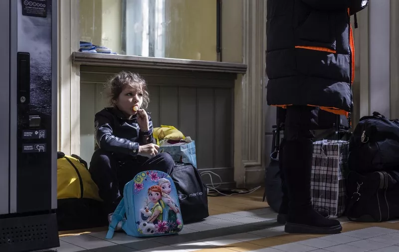 A refugee girl from Ukraine sits with her luggage in the ticket hall of the railway station in Przemysl, eastern Poland, April 7, 2022. - UNHCR, the UN refugee agency, said 4,278,789 Ukrainians had fled across the borders since the war began on February 24 -- a figure up 34,194 since April 5. (Photo by Wojtek RADWANSKI / AFP)